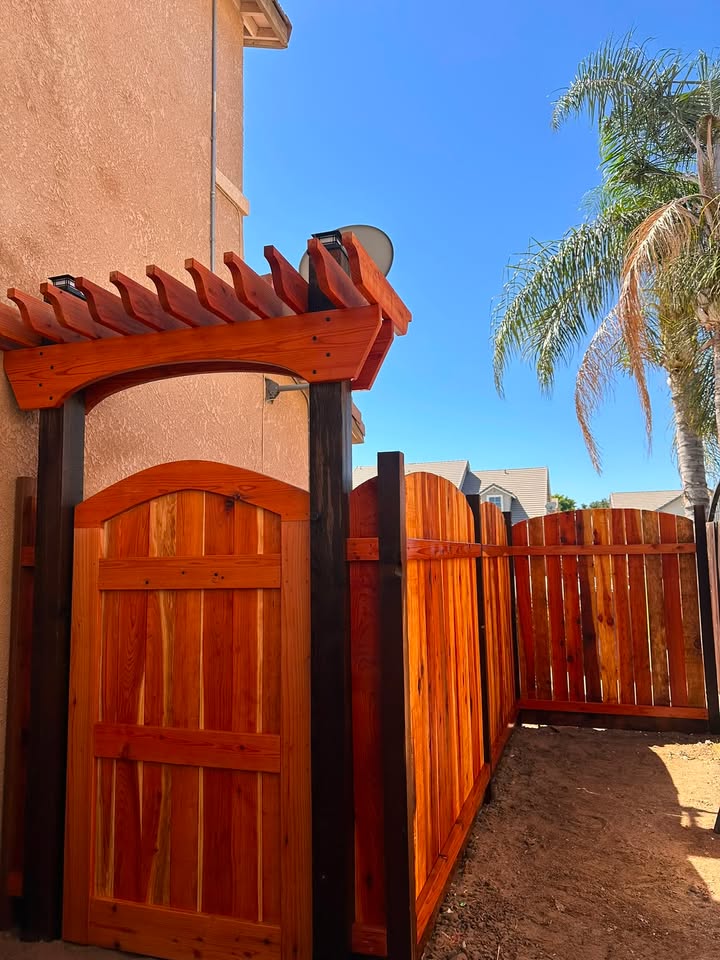 Wood fence and gate with black metal hinges, angled front view